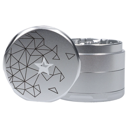Angled close-up of the silver Famous Design Space Aluminum 4pc Grinder showing its geometric star pattern on the top and stacked textured body
