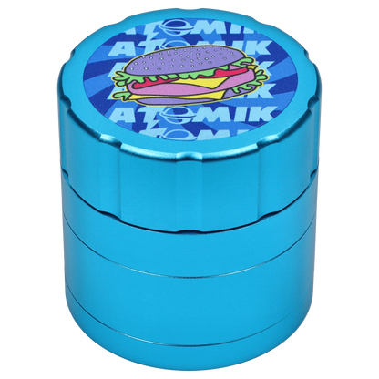 A front view of the Atomik Cheesed 55 mm 3-Stage Grinder, showcasing its blue metallic finish and circular design.