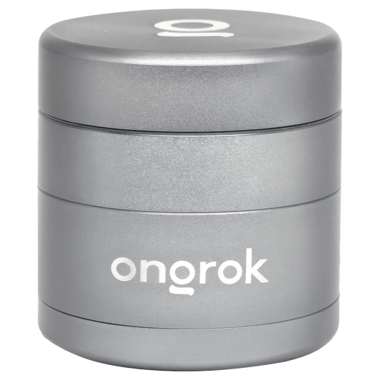 A front view of the Ongrok Mini 4 Piece EZ Grinder in gun metal, showing its circular, multi-part design.