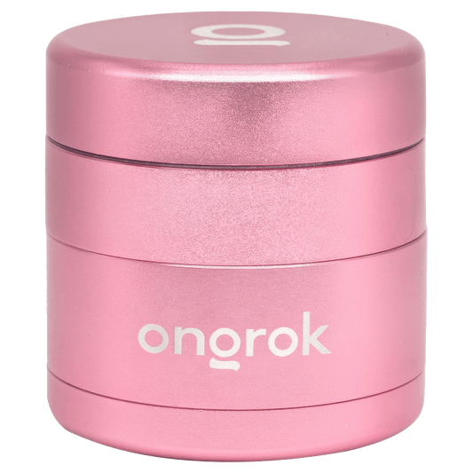 A close-up, angled view of the rose gold Ongrok Mini 4 Piece EZ Grinder, showcasing its metallic finish and compact, multi-tiered design.
