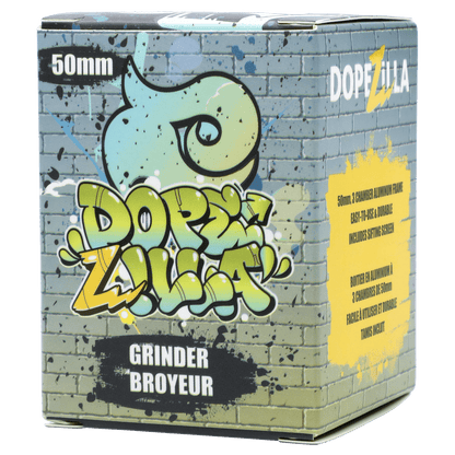 Angled front view of the graffiti‑style Dopezilla Space Pod 3-Stage 50 mm Grinder - Air box showing a brick wall print, colorful logo, and yellow info panel.