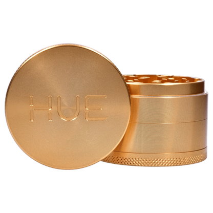 A close-up of the Hue 3-Stage Grinder in champagne gold, showing its stacked, cylindrical design from a slightly elevated angle.