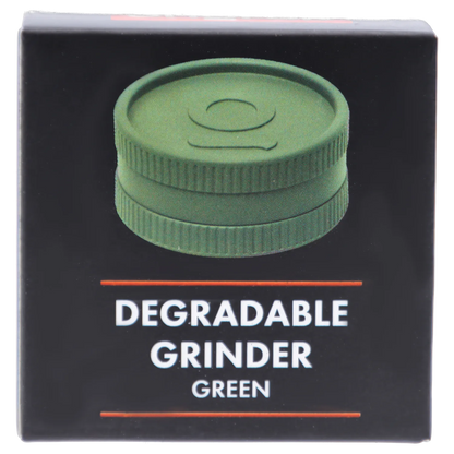 Close-up front view of a green circular Ongrok - Degradable Grinder - 24/box Assorted Colours shown on black packaging with the word "DEGRADABLE" beneath.