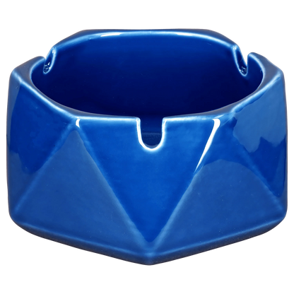 A teal, hexagonal Valiant Hexagonal Glass Ashtray - Teal - 4.4in, captured in a close-up, angled shot emphasizing its smooth, glass construction.