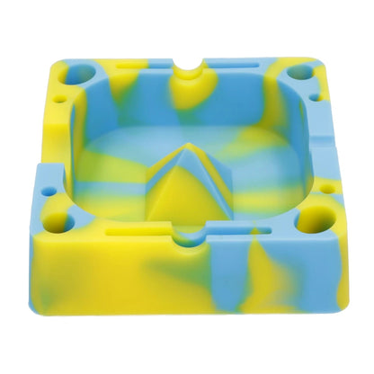 Top-down view of a yellow and blue marbled Valiant Silicone Square Ashtray-Assorted showing its square bowl, central raised pyramid, and rounded corner wells.