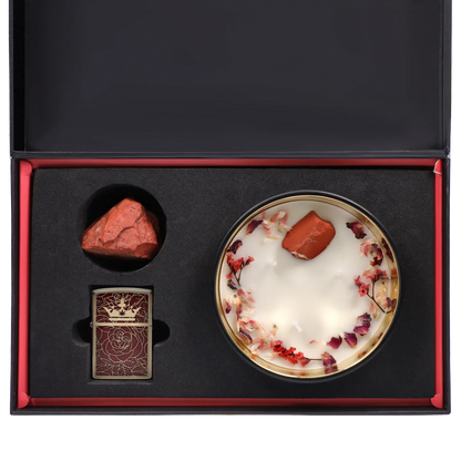 Top-down view of the Queen of Bud: Passion Ritual Box – Candle, Zippo, and Crystal showing a round flower-topped candle, a red raw crystal, and a ornate red Zippo set in black foam.